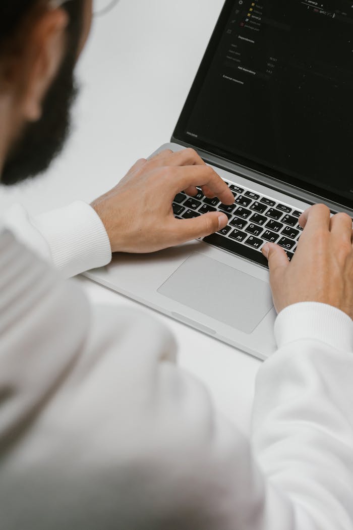 A male programmer intensely typing code on a laptop, showcasing modern technology and software development.